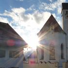 Kirche und Haus mit Sonne dazwischen