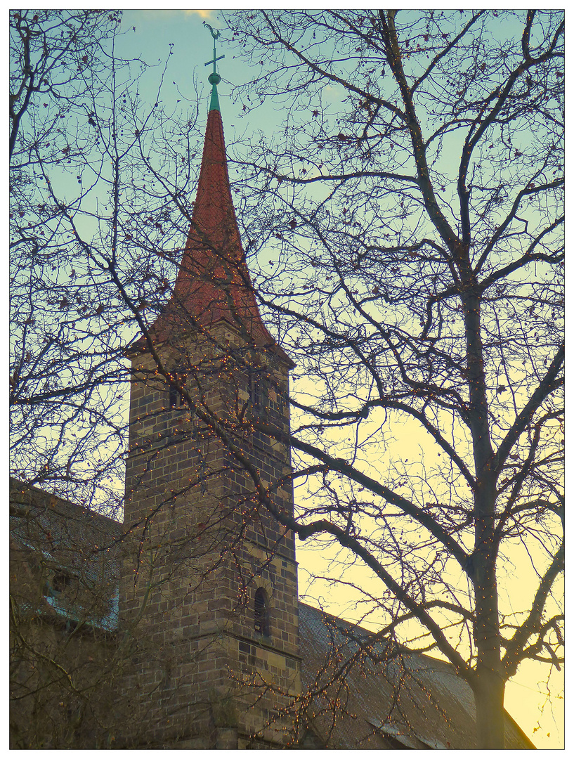 Kirchturm hinter beleuchteten Bäumen