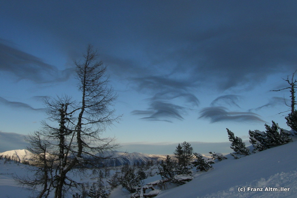 Kleine Wolkenpölster über der schneebedeckten Landschaft