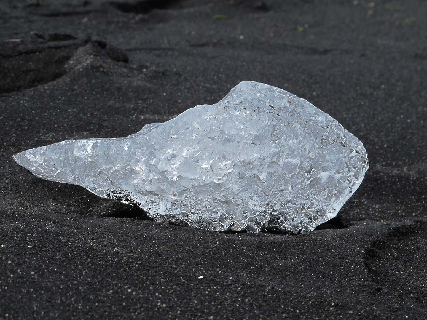 Kleiner Eisbrocken am schwarzen Strand von Jökulsa