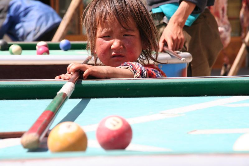 Kleiner Junge beim Billiard-Versuch