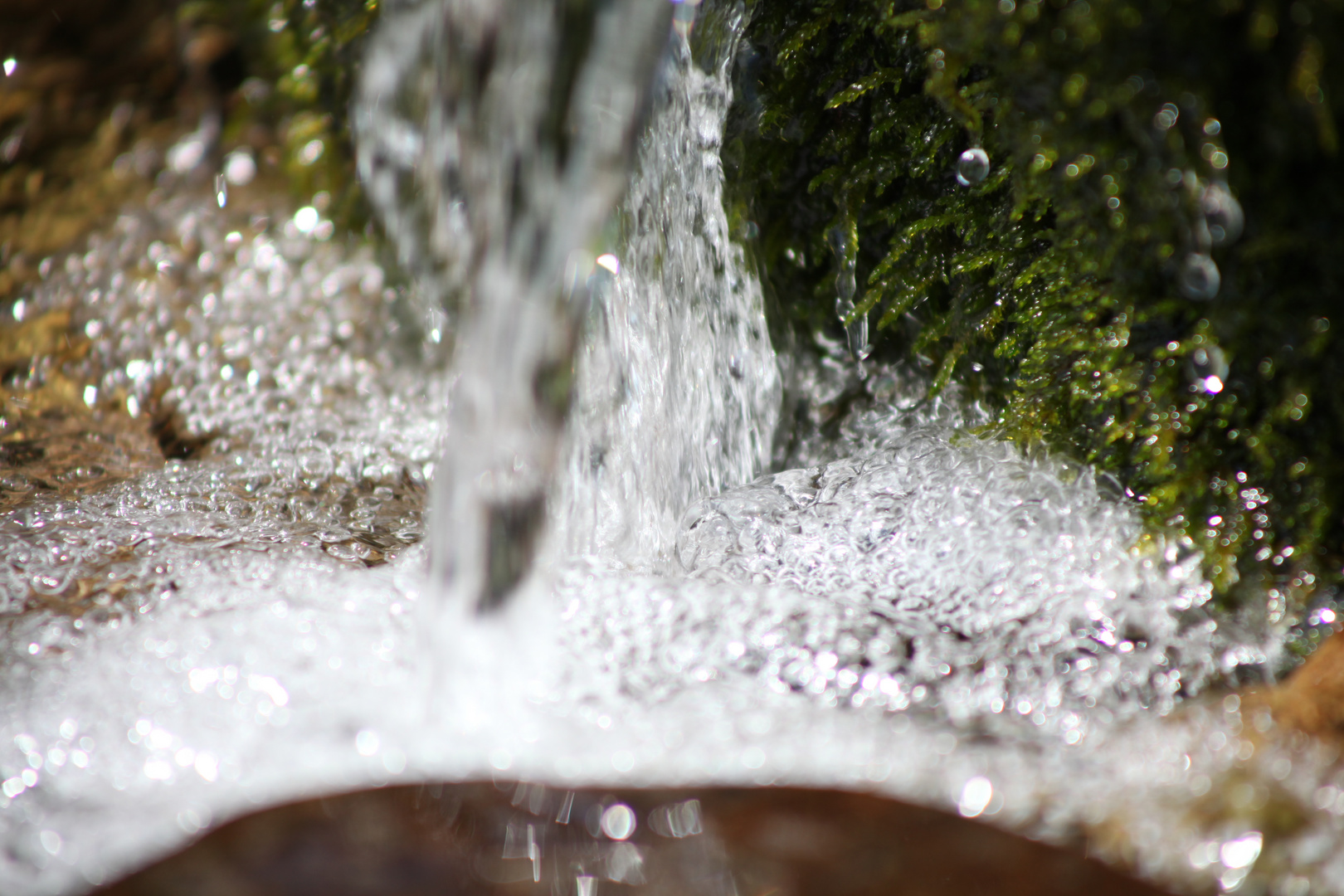 Kleiner Wasserfall mit Moos an einem Gebirgsbach