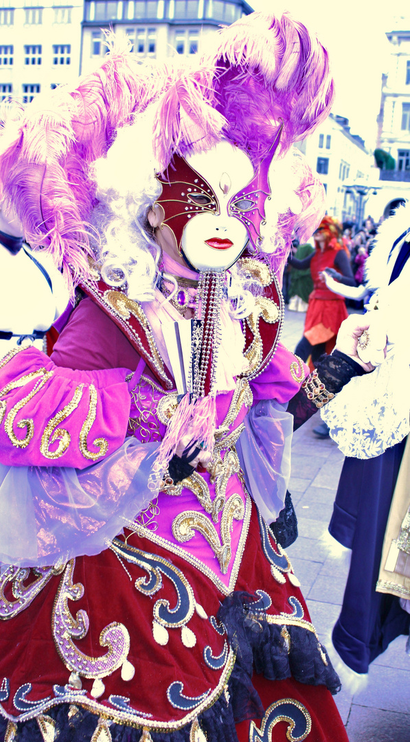 Kostümierte Frau mit Maske und Federschmuck