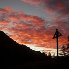 Kreuz vor brennendem Himmel