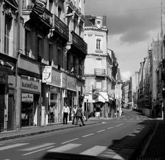 La rue où traverse l' homme à chapeau avec un journal.