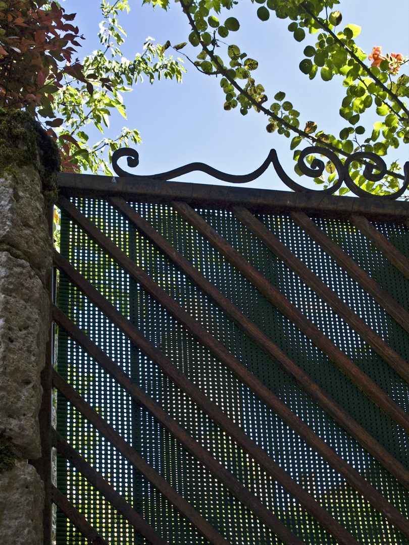 La Tour du Cardinal d’Aux vue à travers la porte d’un jardin à la Romieu