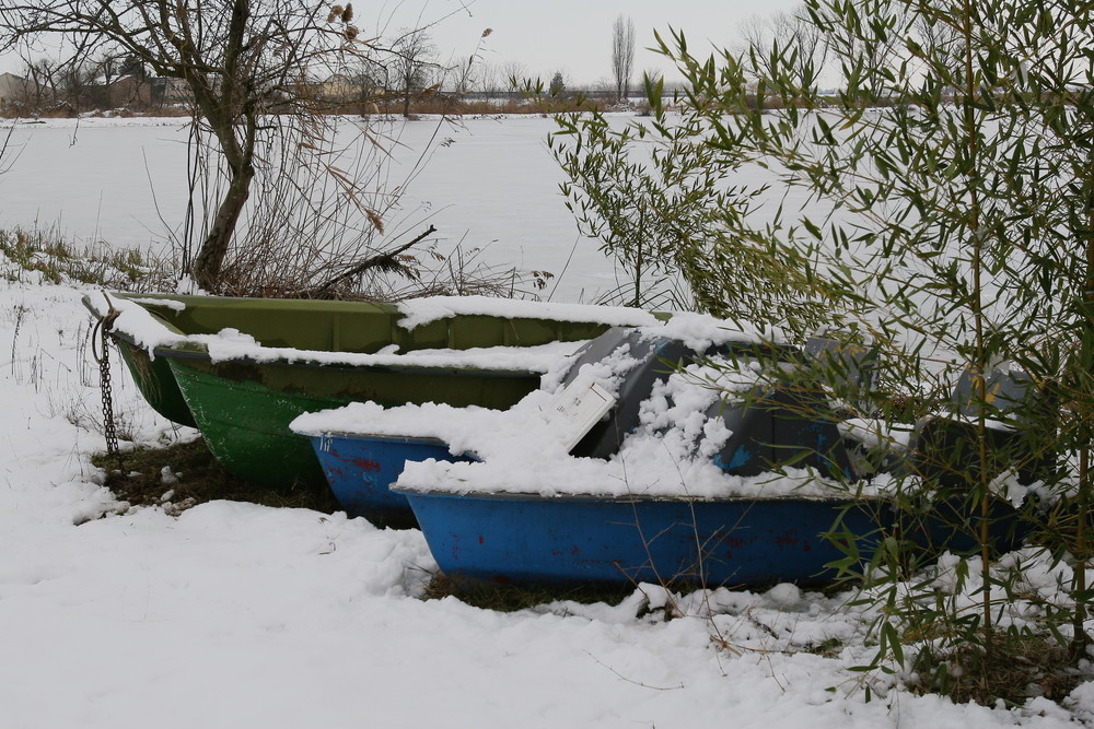 laghetto ghiacciato con barchette innevate