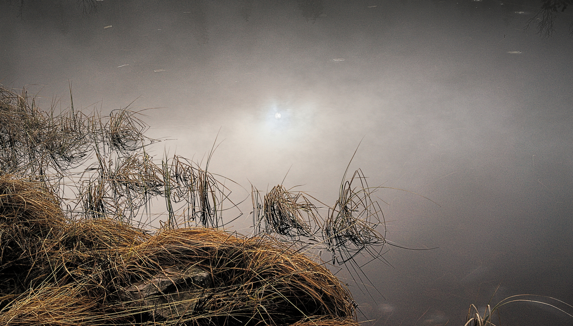 Langsam dringt die Sonne durch den Nebel und spiegelt sich im See