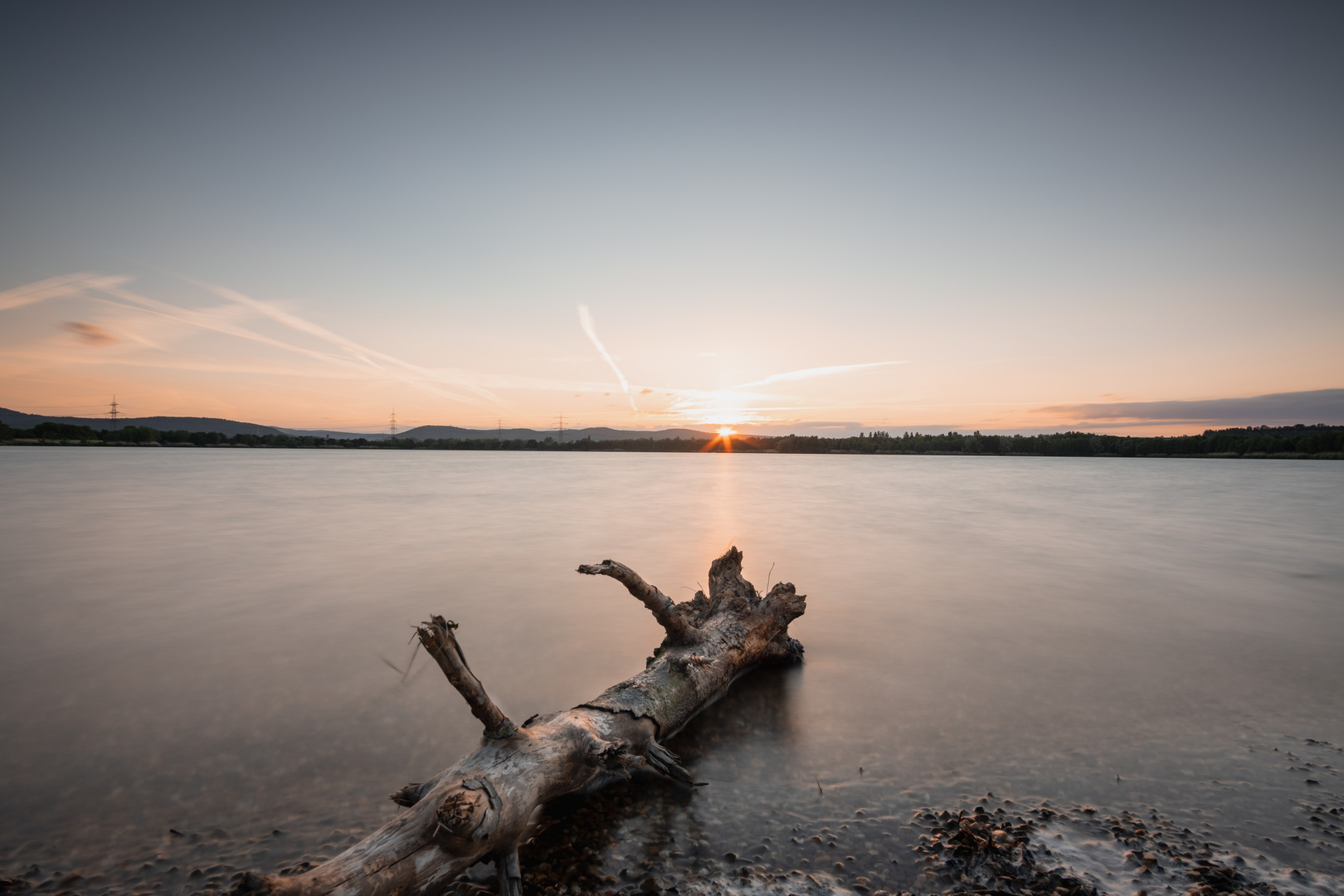 Langzeitbelichtung am See, Baumstamm im Vordergrund 