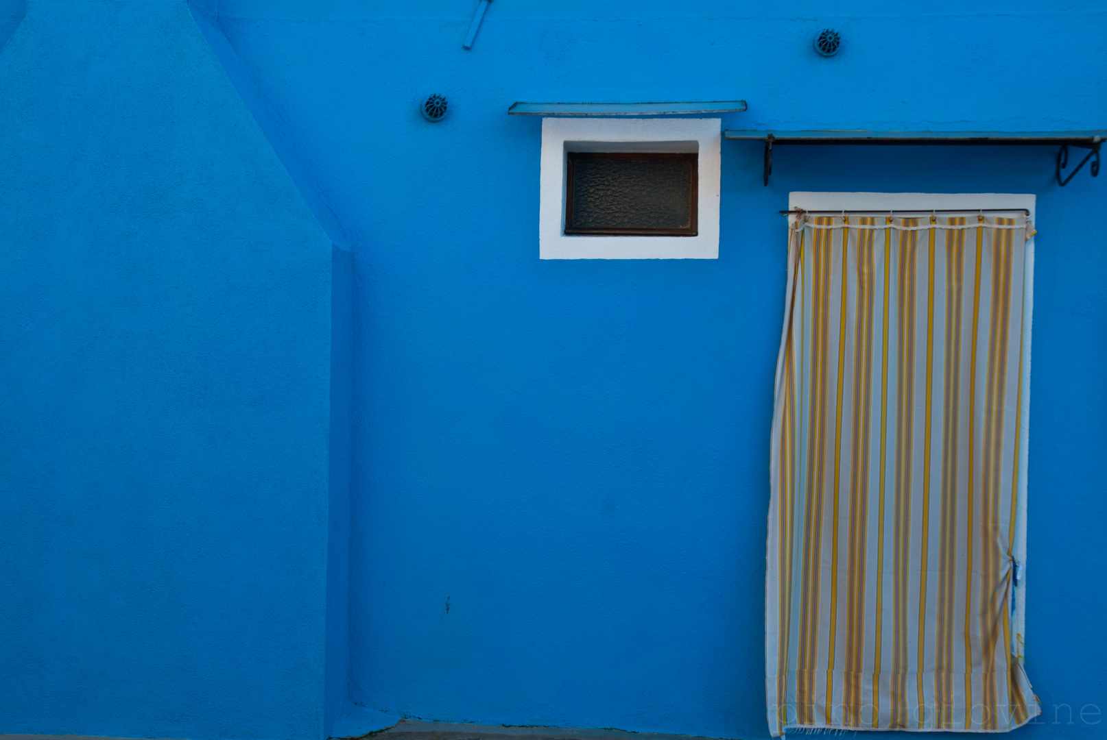 le mur bleu et et le rideau à rayures.