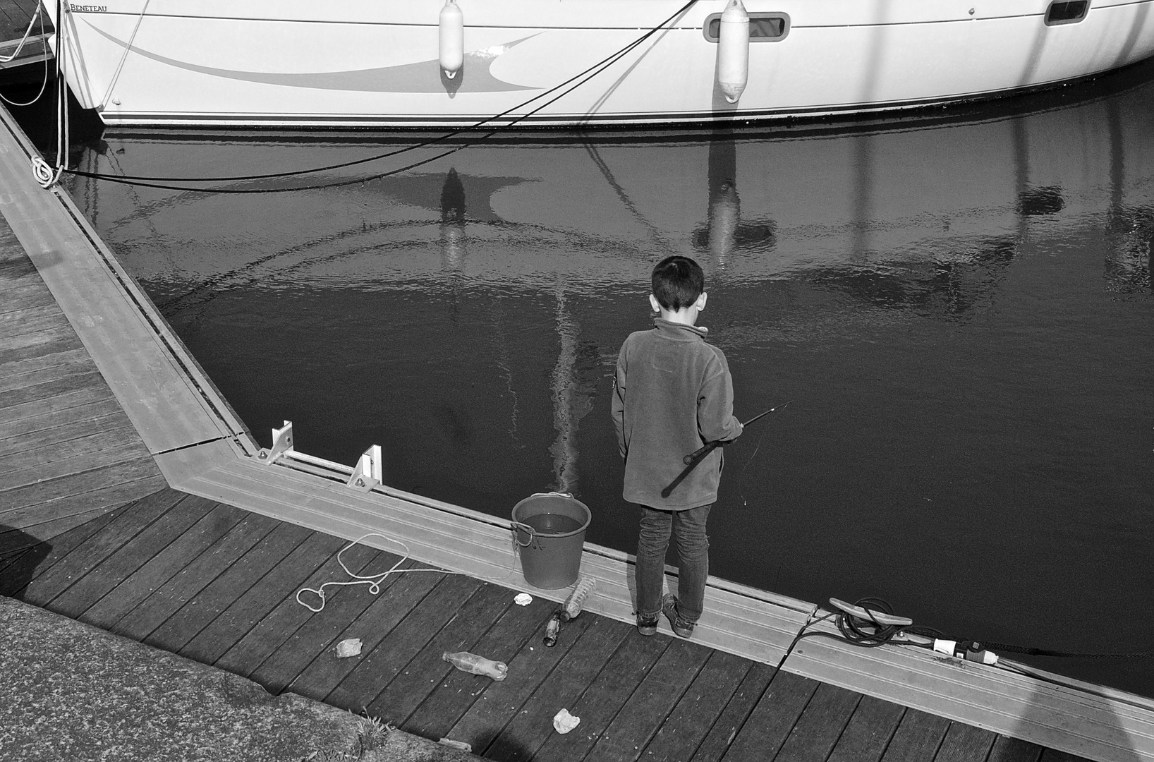 Le petit pêcheur sur le ponton dans le port.