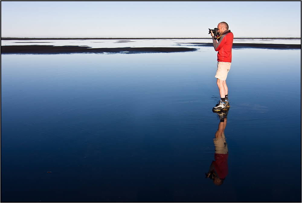 Le photographe rouge sur la plage de sable noir