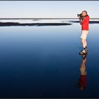 Le photographe rouge sur la plage de sable noir
