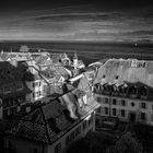 Les toits du bourg de Nyon, le lac Léman et les Alpes.