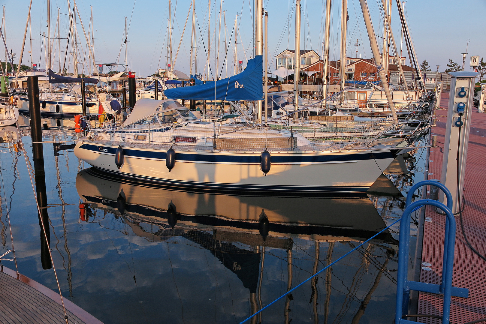 Letzte Sonnenstrahlen scheinen am Abend auf das Segelboot im Neustädter Yachthafen