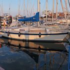 Letzte Sonnenstrahlen scheinen am Abend auf das Segelboot im Neustädter Yachthafen