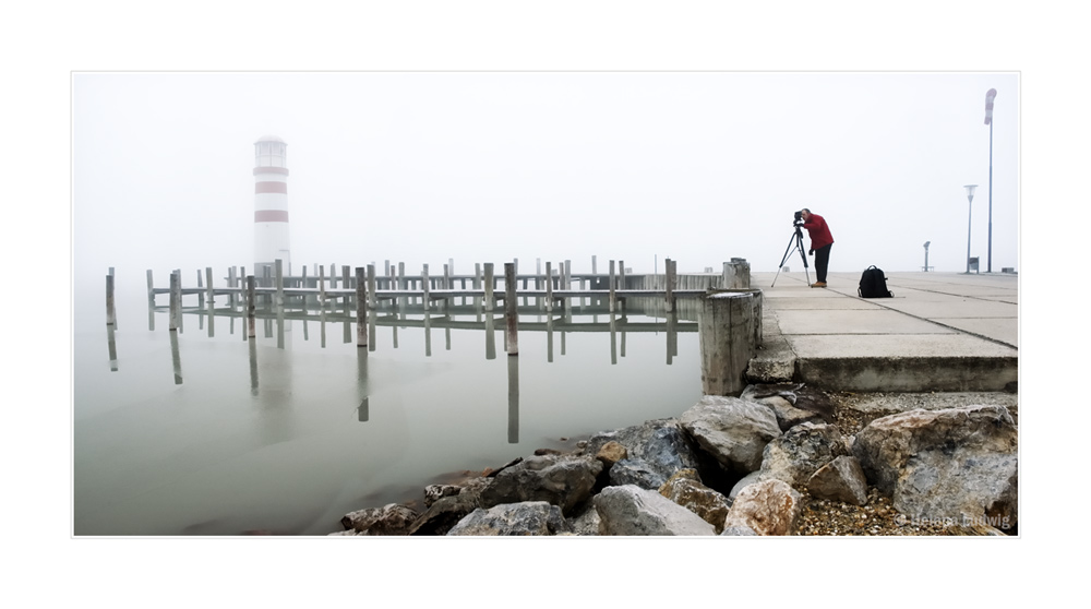 Leuchtturm im Nebel und Fotograf bei der Arbeit