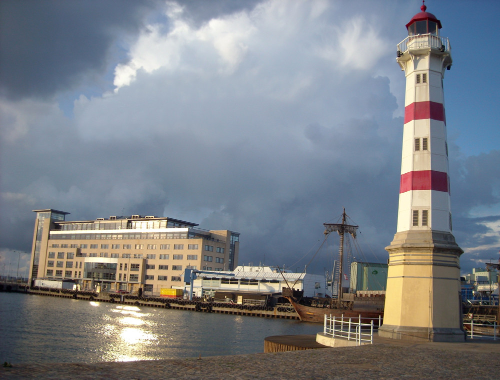 Leuchturm unter Regenwolken sonnenlichtbeschienen