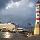 Leuchturm unter Regenwolken sonnenlichtbeschienen