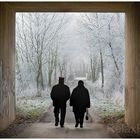 "Licht am Ende des Tunnels" - Seniorenpaar beim Spaziergang durch Straßentunnel im Winter