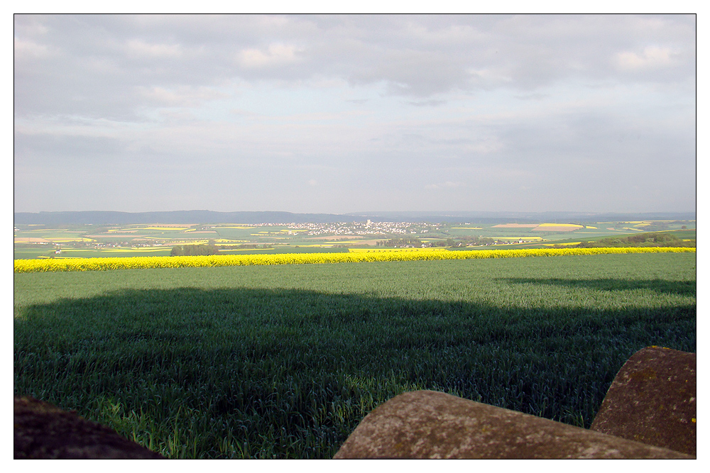 Licht, Schatten, Wolken, Raps und das Dach einer Friedhofskapelle