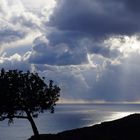 Licht strahlt durch dunkle Regenwolken über dem Meer