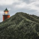 Lit lighthouse on a hill with tall grass and moss on Sylt island