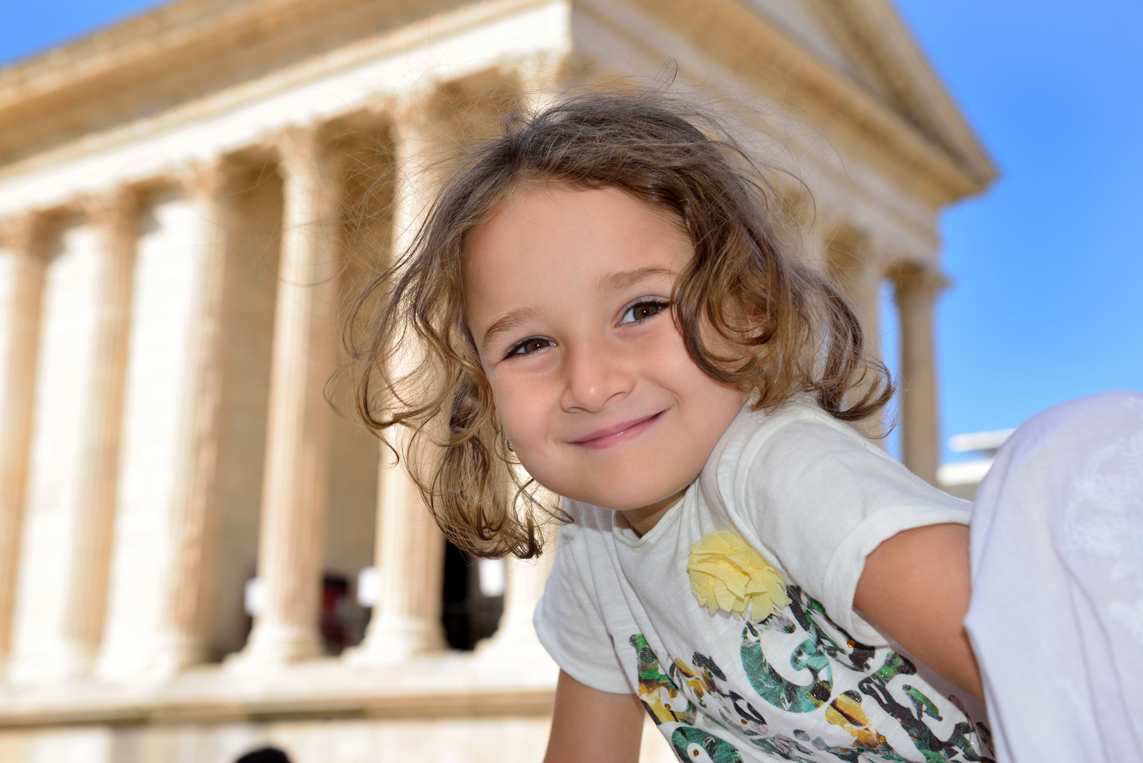 Little girl posing in front of a roman temple