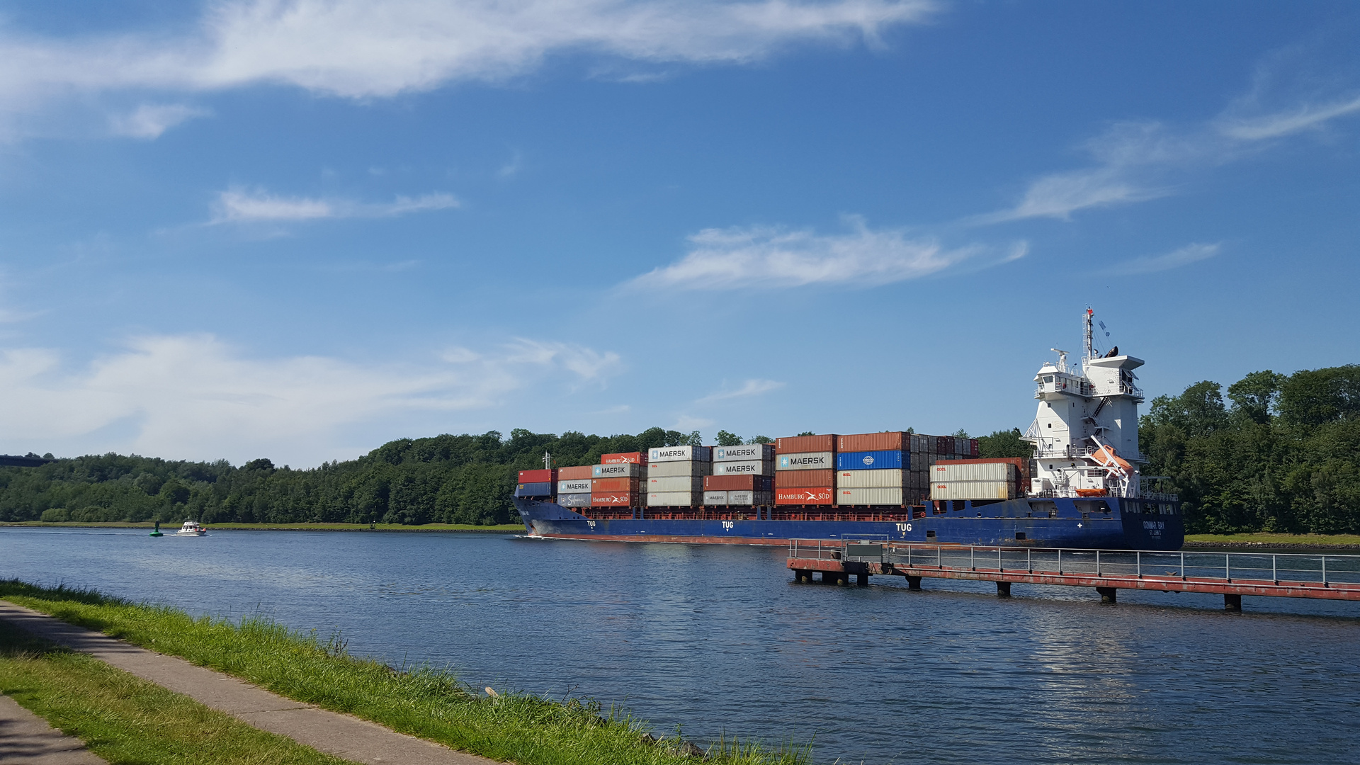 little yacht meeting a cargo vessel on a sunny day