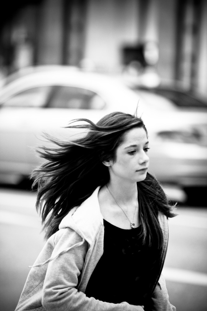 long hair. windy. she. moving. car in the back...