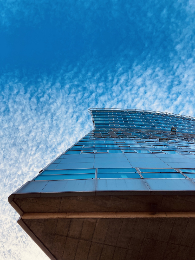 Looking up a high rise building which resembles a cruise ship