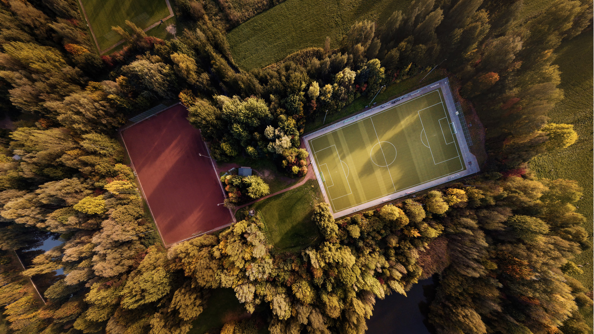 Luftaufnahme eines Sportplatzes im Herbst bei Sonnenunterganng