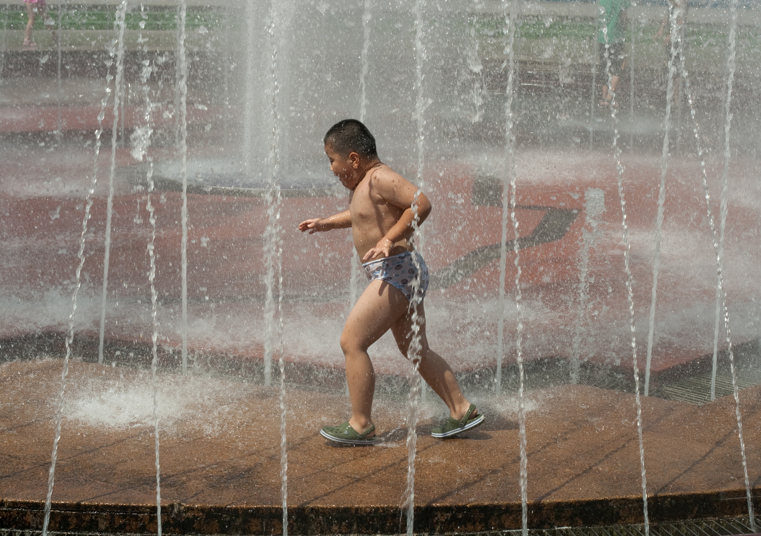 Lustiger Junge rennt durch Brunnen