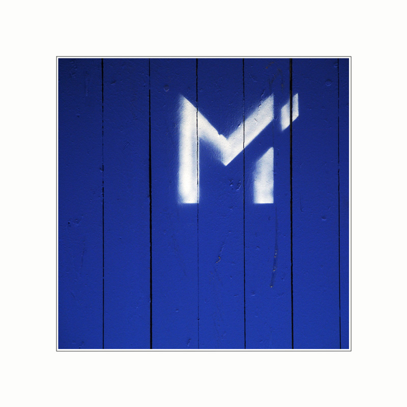 M (weiß) auf Holzbretter (blau)