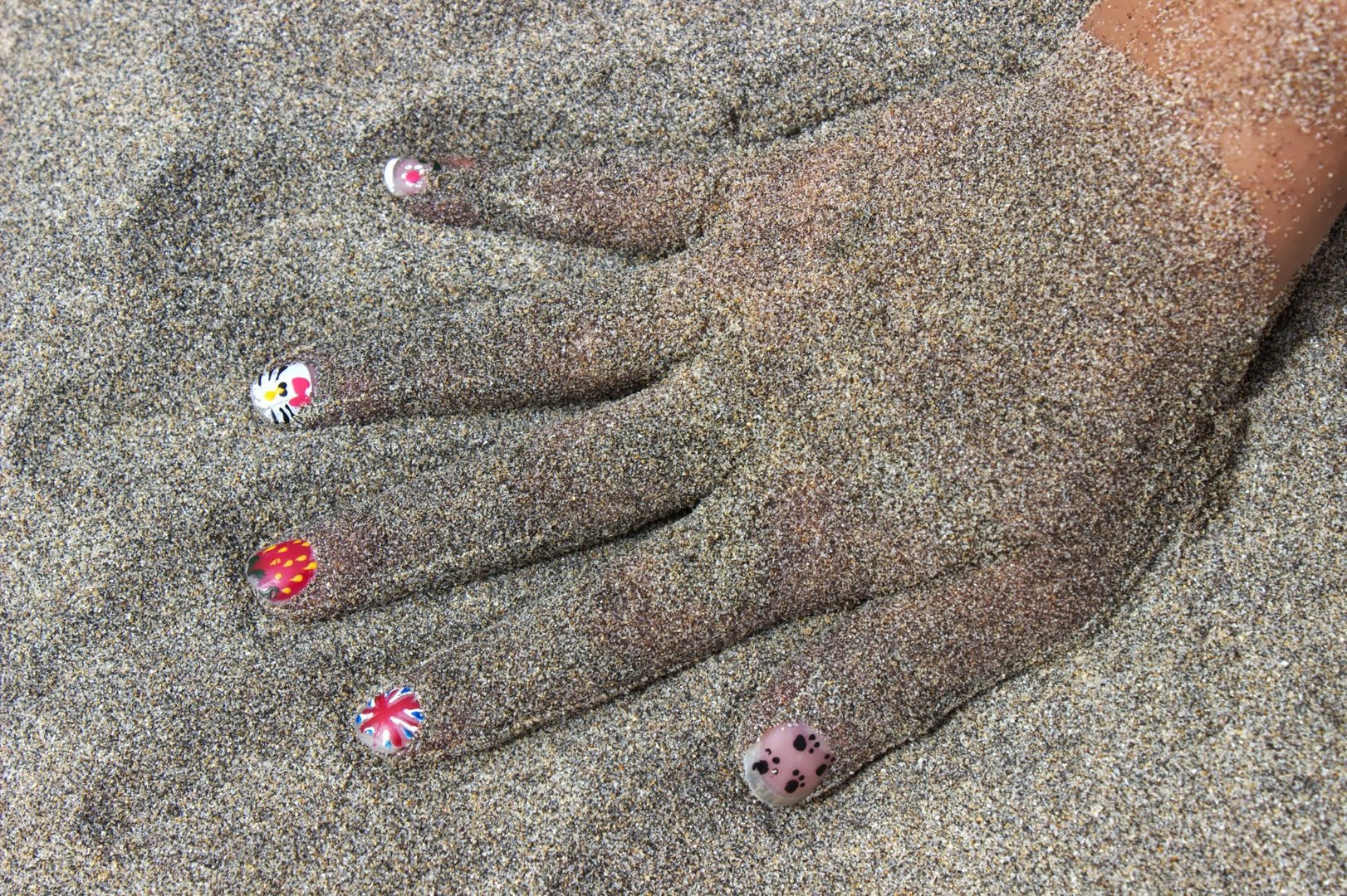 Mädchenhand im Sand