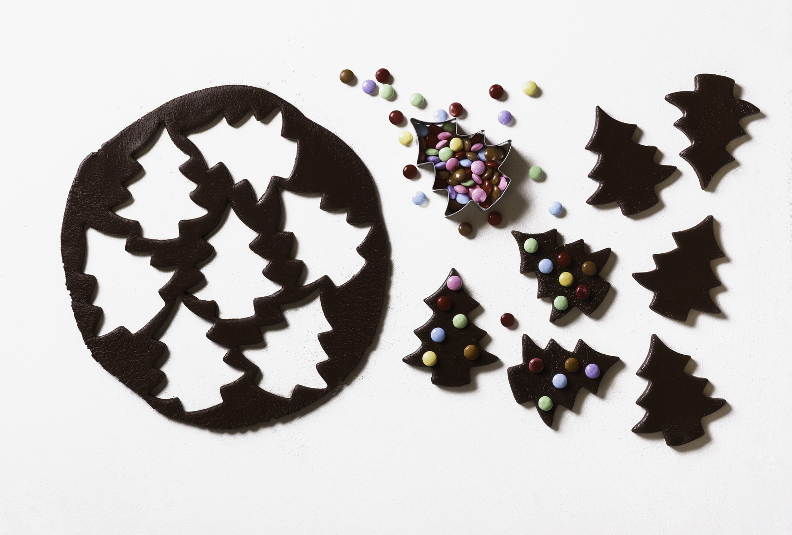 Making Christmas tree cookies with colorful candies. Gingerbread