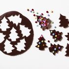 Making Christmas tree cookies with colorful candies. Gingerbread