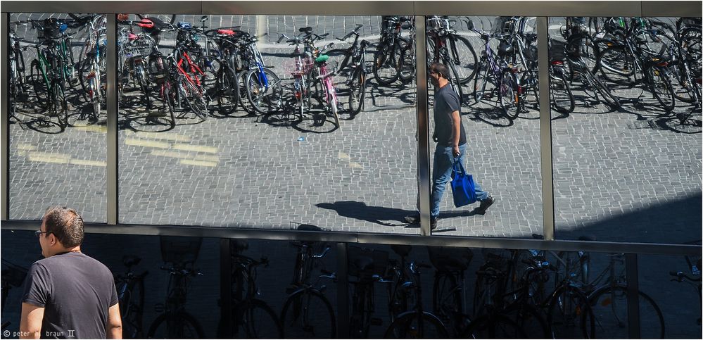 Mann im Spiegel, eine blaue Stofftasche tragend...