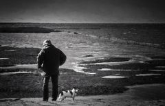 Mann mit Hund am Nordseestrand