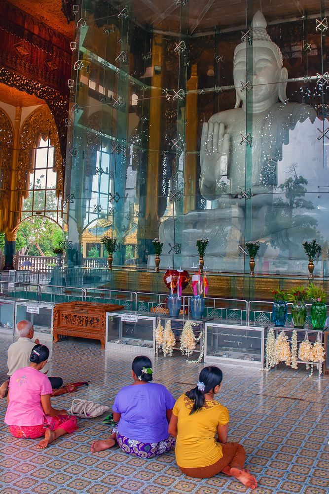 Marble Buddha behind a glas shield