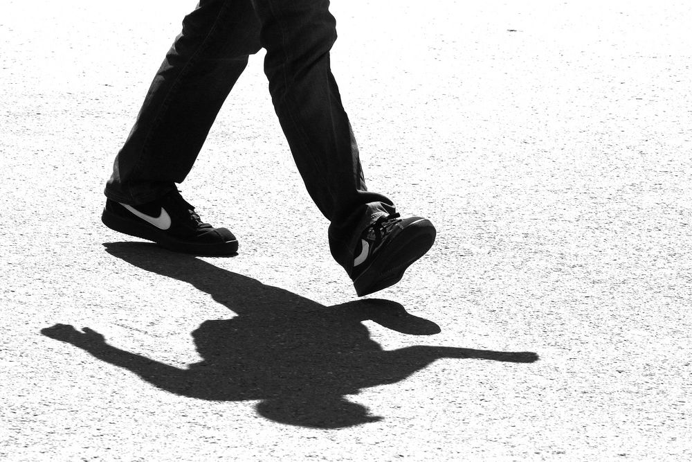 Markenschuhe treten auf einen dunklen Schatten