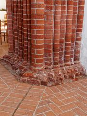 Marode Details am Fuß eines Backsteinpfeilers der Pilsumer Kreuzkirche (Ostfriesland)