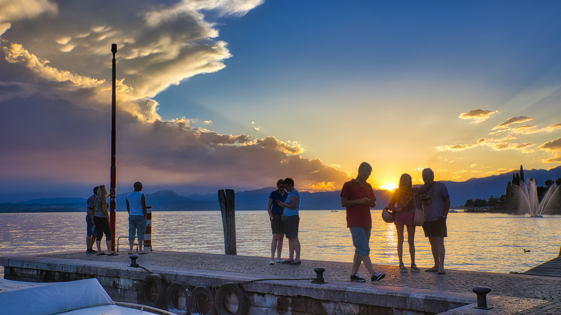 Menschen beobachten den Sonnenuntergang am Garadsee