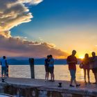 Menschen beobachten den Sonnenuntergang am Garadsee