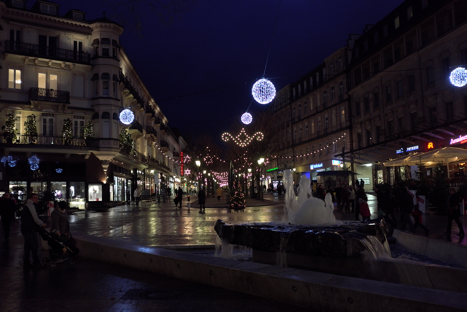 Menschen in einer vorweihnachtlich beleuchteten nächtlichen Stadt