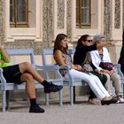 Menschen sitzen auf einer Bank und beobachten andere Menschen....