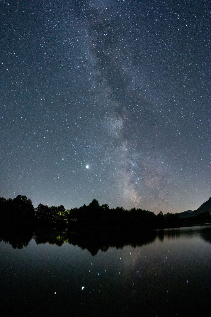 Milchstraße spiegelt sich in kleinem See im Chiemgau. 