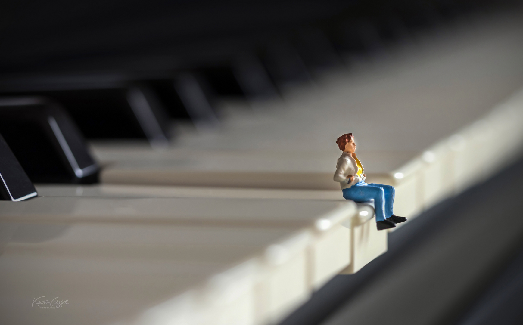 miniature woman sitting on piano 