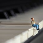 miniature woman sitting on piano 