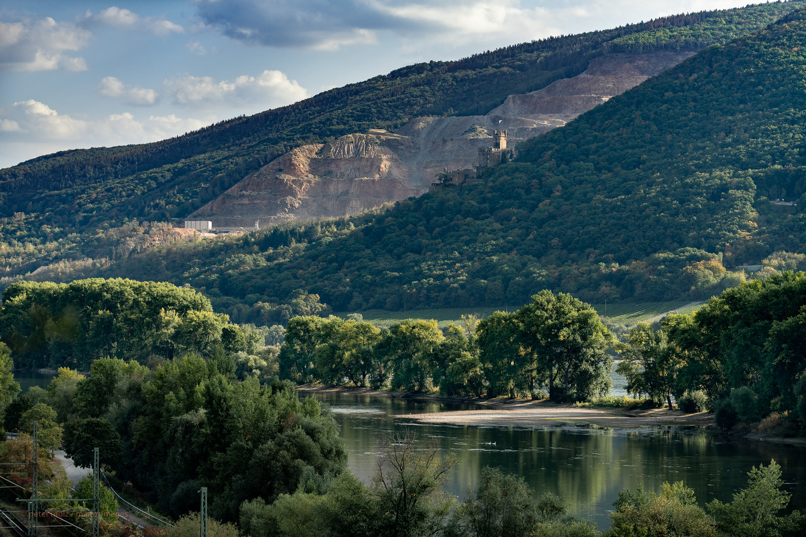 Mittelrheintal - Über dem Rhein, hinter der Burg, die klaffende Wunde im bewaldeten Berg